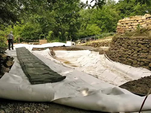 Die abgerollte Teichfolie liegt neben der Grube