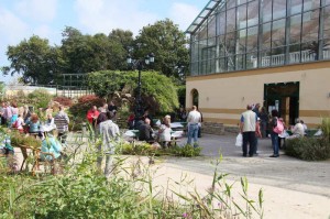 Besucher entspannen vor der Palmenhalle, Snacks bietet die Grillstation